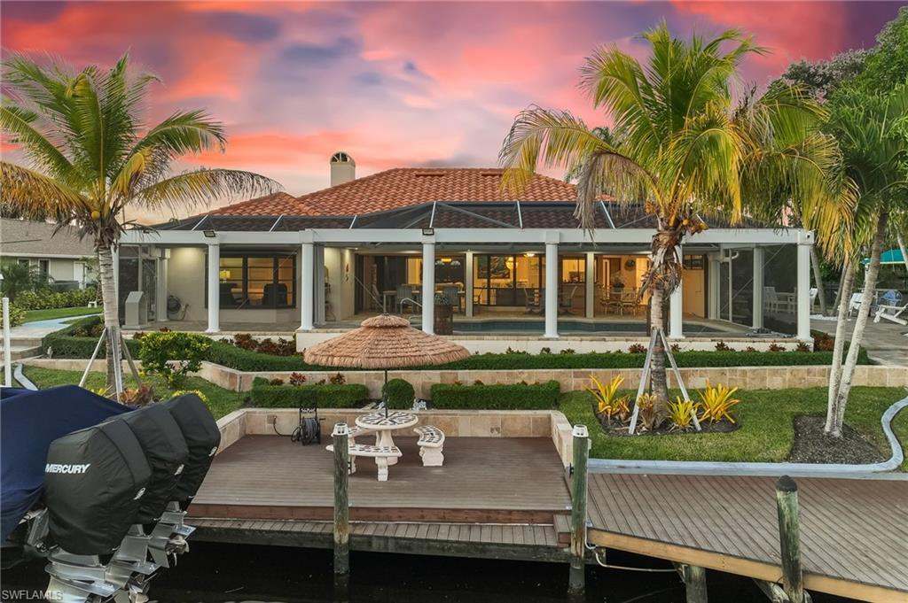 Image 1: Back of property at dusk with a sunroom, a chimney, and a lanai