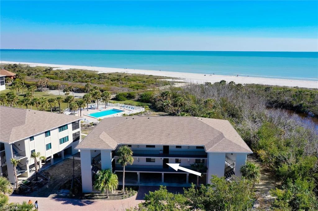 Image 2: Coastal residential building featuring multiple levels and balconies, with a sandy beach and turquoise ocean visible in the background