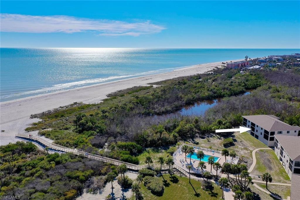 Image 3: Extensive beachfront property featuring a multi-story building, an outdoor swimming pool, and a boardwalk accessing a wide sandy beach