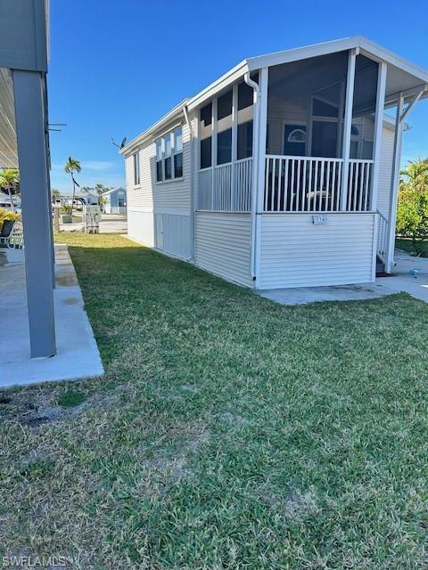 Image 4: View of side of home with a sunroom and a lawn