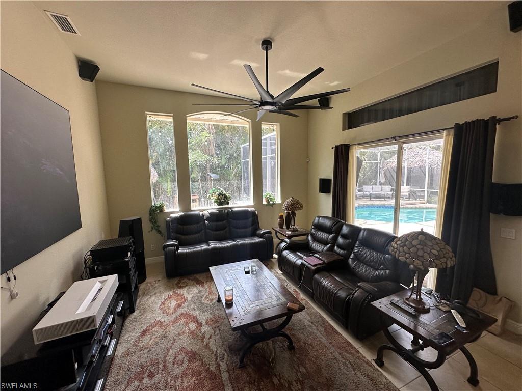 Image 4: Living area with light tile patterned floors and a ceiling fan