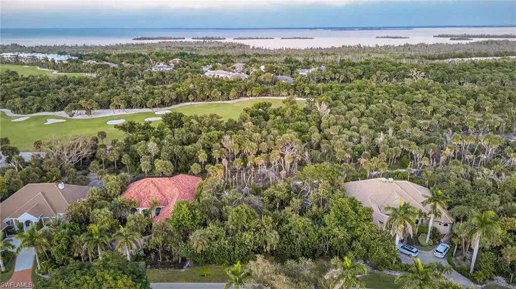 Image 1: Aerial view of residential area featuring a nearby body of water and a local golf course