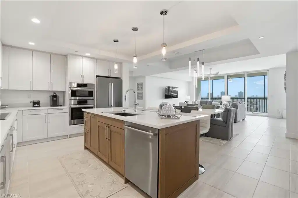 Image 1: Kitchen featuring a tray ceiling, white cabinets, open floor plan, appliances with stainless steel finishes, and recessed lighting - Virtually Edited Image