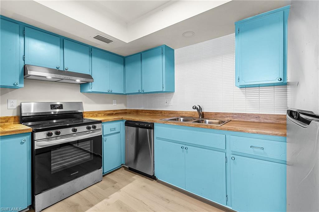 Image 2: Refreshed kitchen w/tropical Key West Blue cabinets, 'butcher block' countertops, modern tile backsplash, and stainless steel appliances.