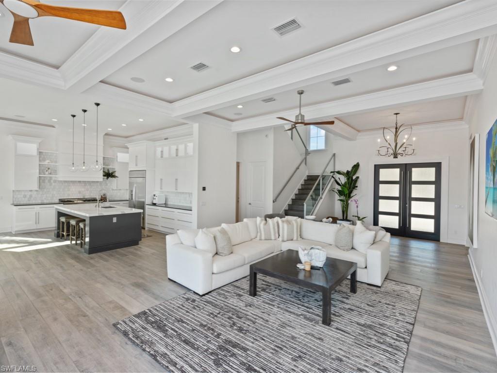 Image 2: Living room with french doors, ceiling fan with notable chandelier, ornamental molding, and light hardwood / wood-style flooring