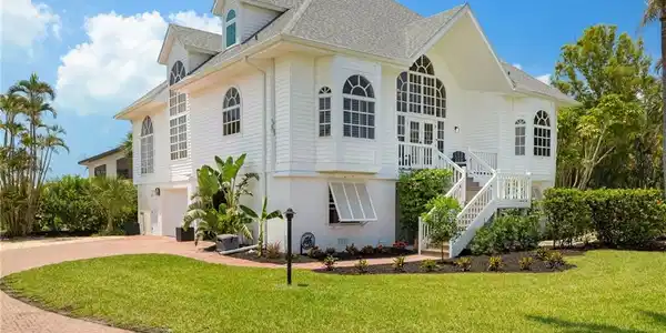 Image 2: View of property exterior featuring roof with shingles, decorative driveway, stairs, and a lawn