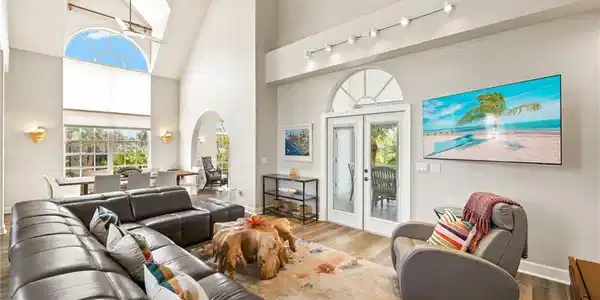 Image 4: Living room featuring high vaulted ceiling, french doors, plenty of natural light, arched walkways, and wood finished floors