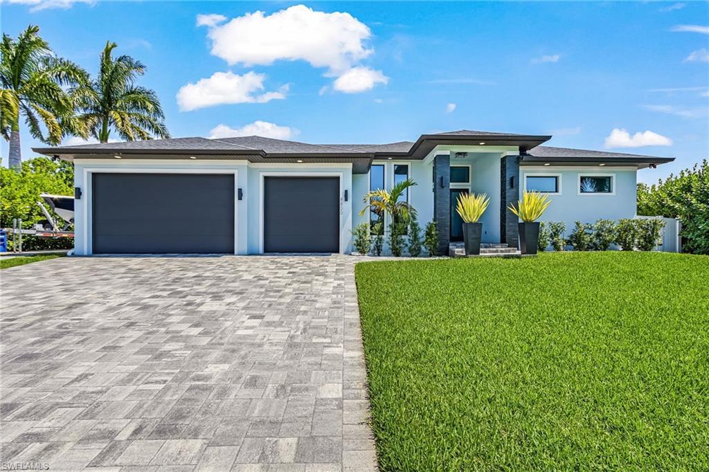 Image 1: Contemporary exterior featuring a paver driveway, two-car garage, and lush green lawn