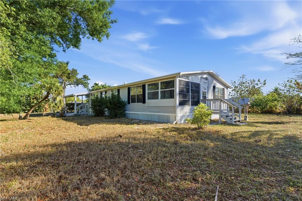 Image 3: View of property exterior featuring a sunroom and a lawn