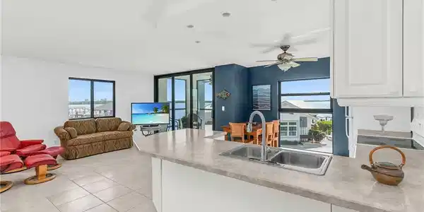Image 4: Kitchen with light tile patterned floors, a sink, open floor plan, a peninsula, and white cabinetry