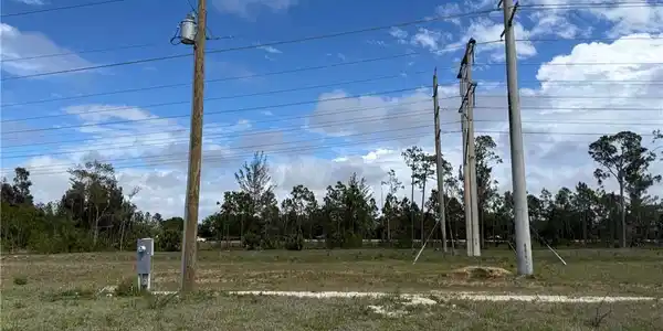 Image 4: Expansive raw land parcel featuring a utility pole with an attached transformer, overhead power lines, and a dedicated utility box