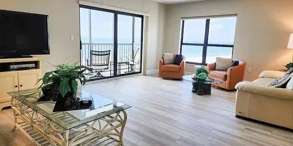 Image 2: Living area featuring light wood look plank luxury vinyl floors, hurricane rated slider to beachfront balcony and large picture windows to add even more coastal natural light to this relaxing resort style beach retreat!