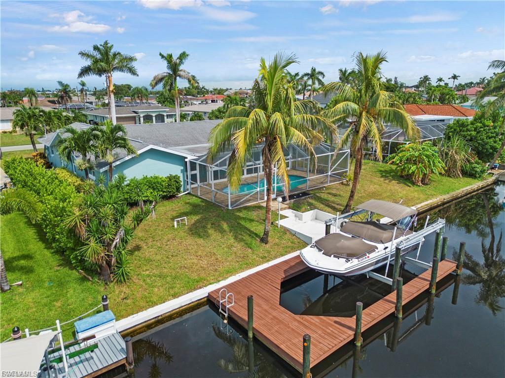 Image 1: Dock area featuring boat lift, a lawn, a sunroom, and a water view