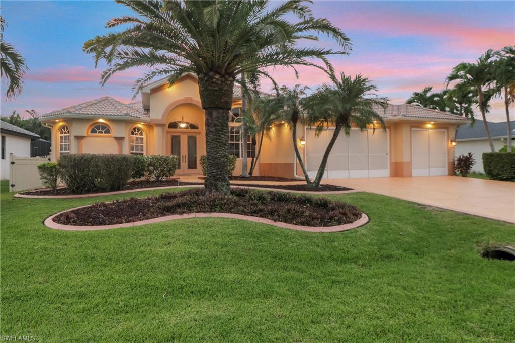 Image 1: Mediterranean / spanish-style house with stucco siding, a front lawn, a garage, french doors, and driveway