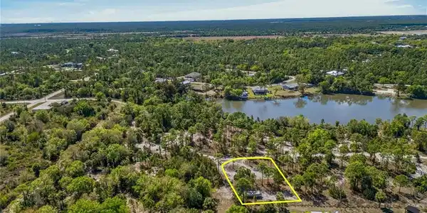 Image 2: Aerial view of property and surrounding area with property parcel outlined and a large body of water