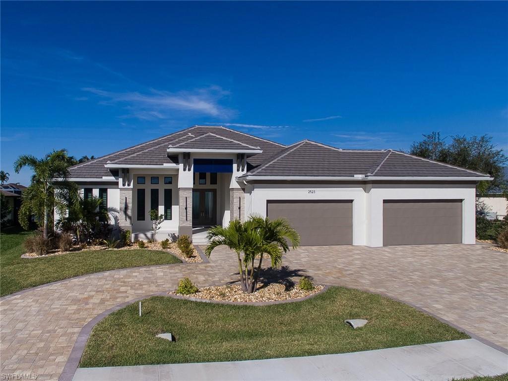 Image 3: Prairie-style home featuring a tile roof, stucco siding, a front yard, decorative driveway, and a garage