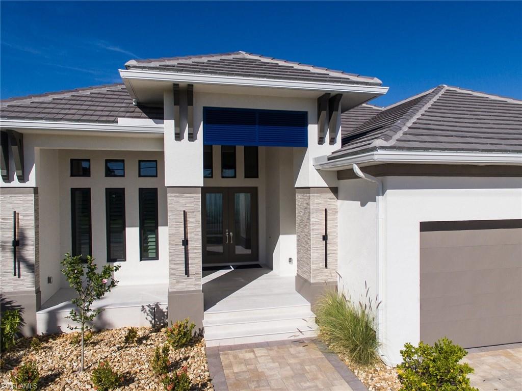 Image 4: Property entrance with stone siding, a tile roof, stucco siding, french doors, and a garage