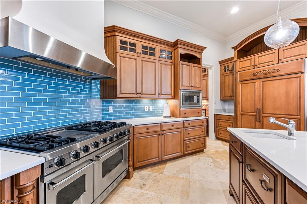 Image 3: Kitchen featuring backsplash, sink, wall chimney range hood, pendant lighting, and built in appliances