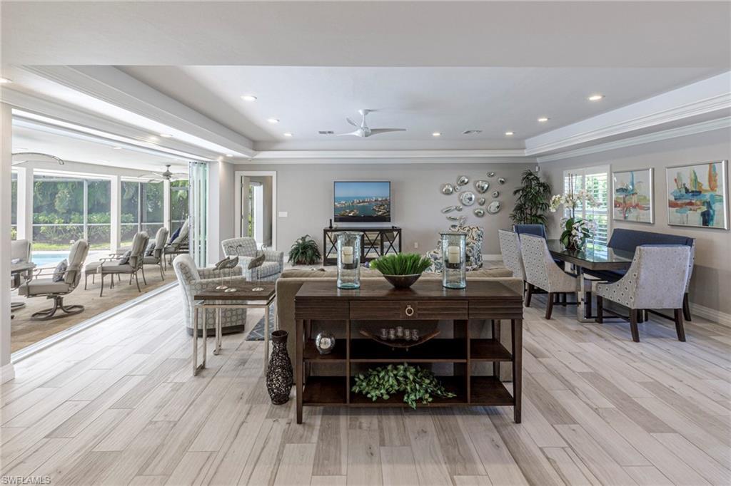 Image 3: Dining room featuring light wood-type flooring, ornamental molding, ceiling fan, and a raised ceiling