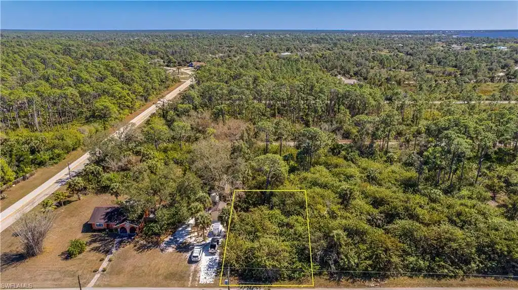 Image 1: Aerial overview of property's location with property parcel outlined and a heavily wooded area