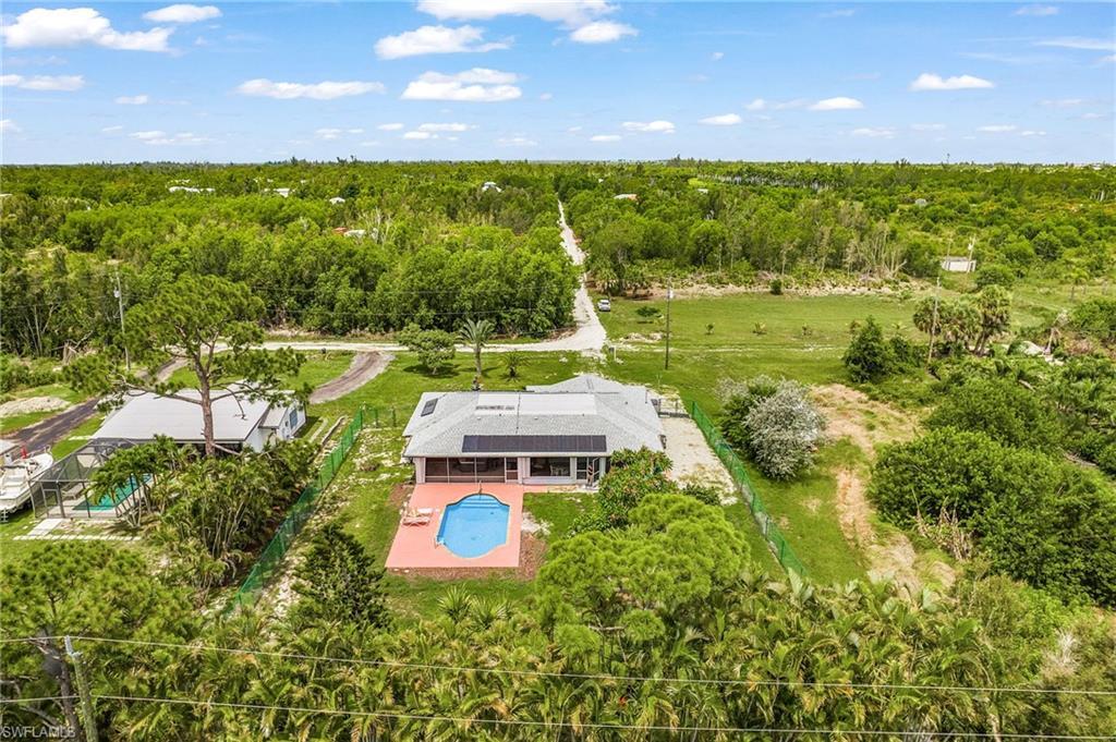 Image 2: Aerial perspective showcasing the property's exterior, featuring a swimming pool, a surrounding paved patio, and a fenced yard