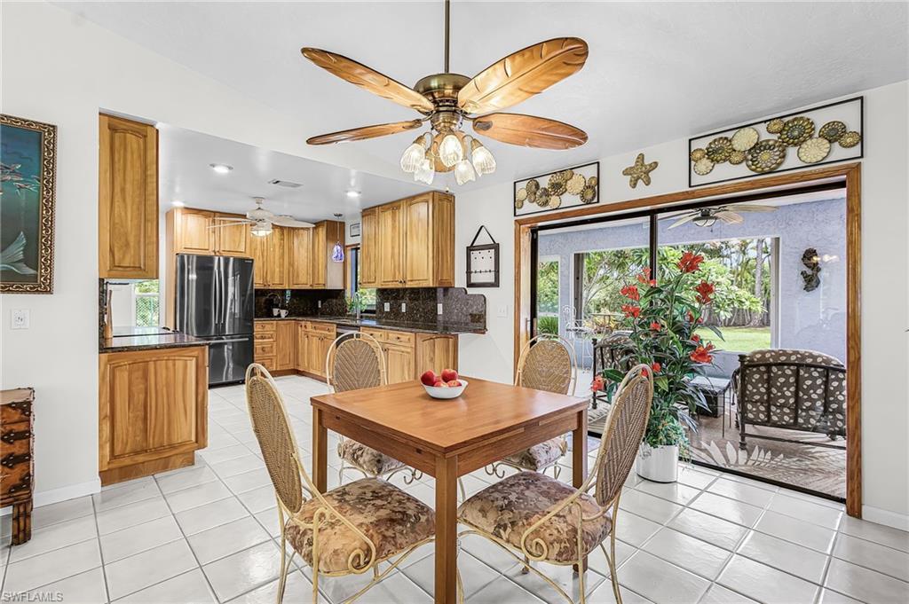 Image 4: Open-concept kitchen and dining area featuring wood cabinetry, dark granite countertops, and stainless steel appliances