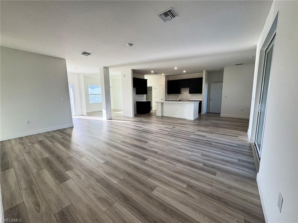 Image 3: Unfurnished living room featuring wood finished floors, recessed lighting, baseboards, and a textured ceiling