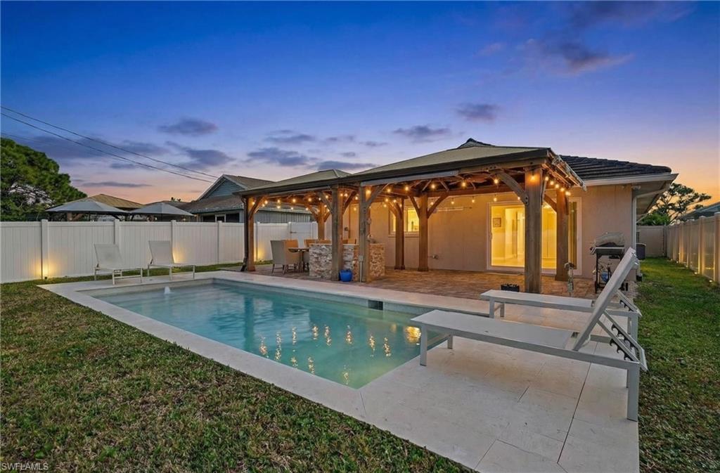 Image 3: Back of house at dusk with a fenced backyard, a patio area, and stucco siding