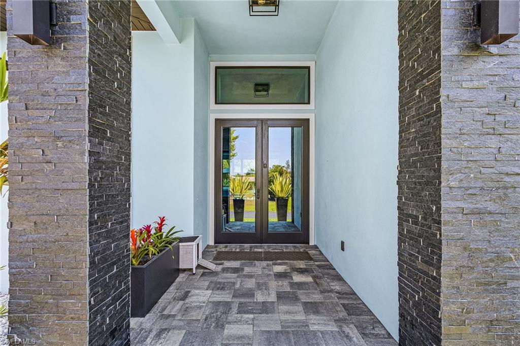 Image 2: Entryway featuring stacked stone pillars, a double glass-panel door, and a transom window