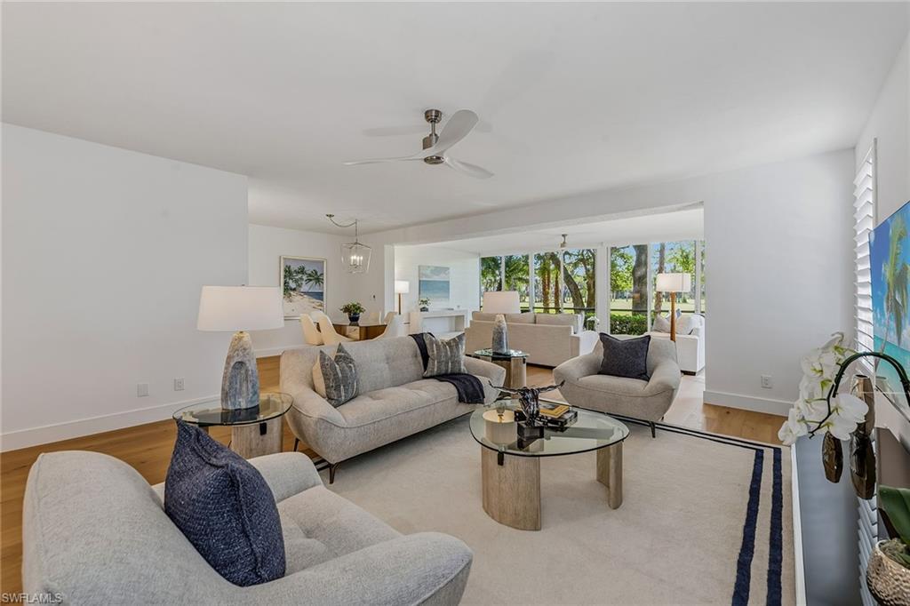 Image 4: Living area with wood finished floors, ceiling fan, and a chandelier