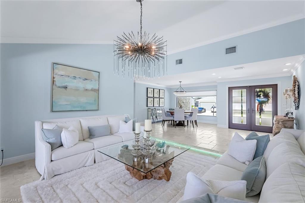 Image 4: Formal living room looking toward double door hurricane impact entry. Multi colored custom lighting on floor.