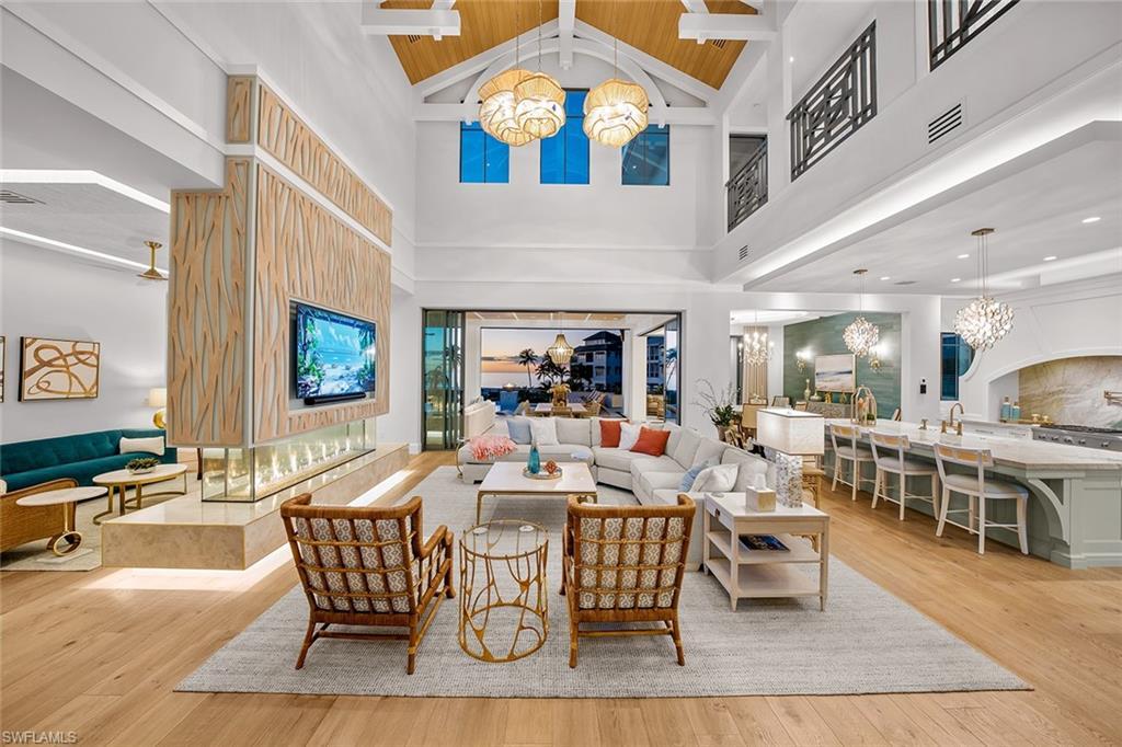 Image 2: Living area with a chandelier, beamed ceiling, light wood-style floors, and high vaulted ceiling
