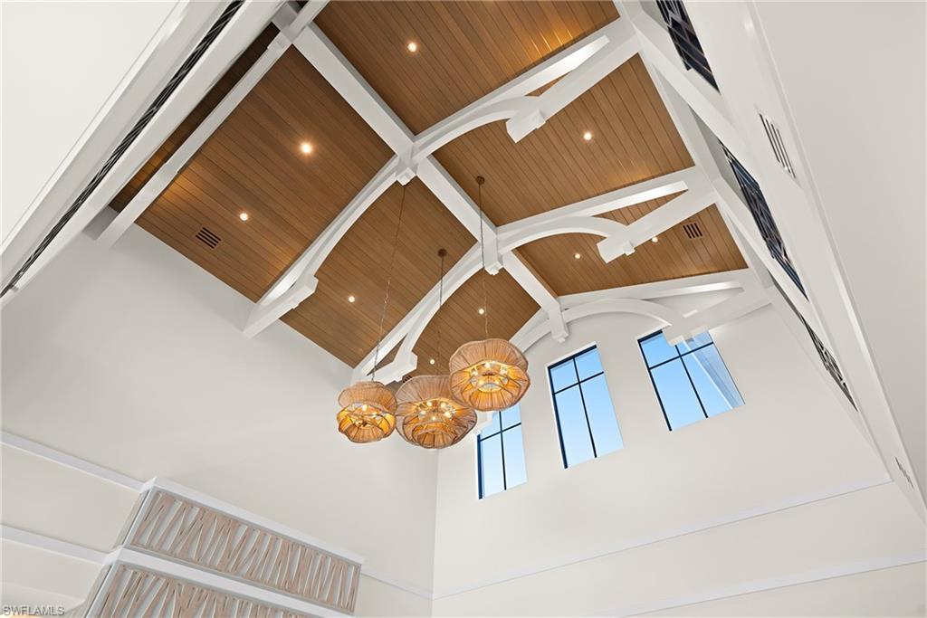 Image 4: Detailed view of a chandelier, a skylight, and a wooden ceiling with exposed beams