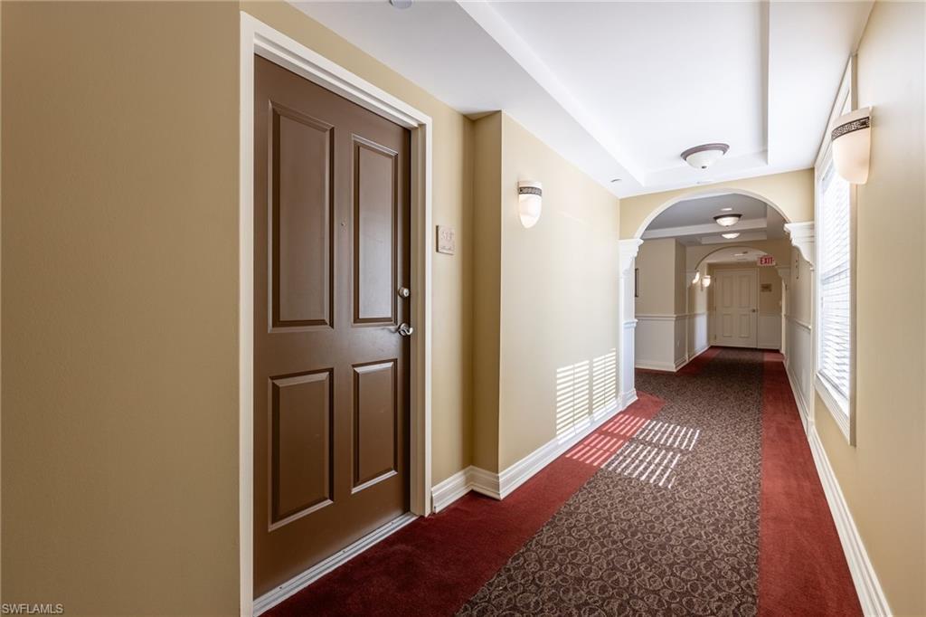Image 4: Hallway featuring arched walkways and dark colored carpet