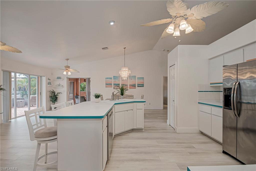 Image 2: Kitchen featuring white cabinets, a ceiling fan, appliances with stainless steel finishes, a breakfast bar, and vaulted ceiling