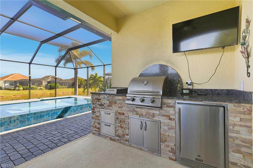 Image 2: View of patio / terrace with an outdoor pool, a sunroom, a lanai, and exterior kitchen