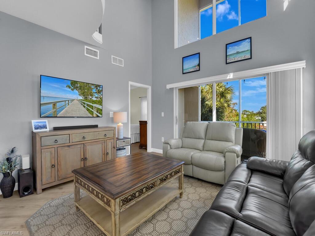 Image 4: Living room featuring light wood-style flooring and a high ceiling
