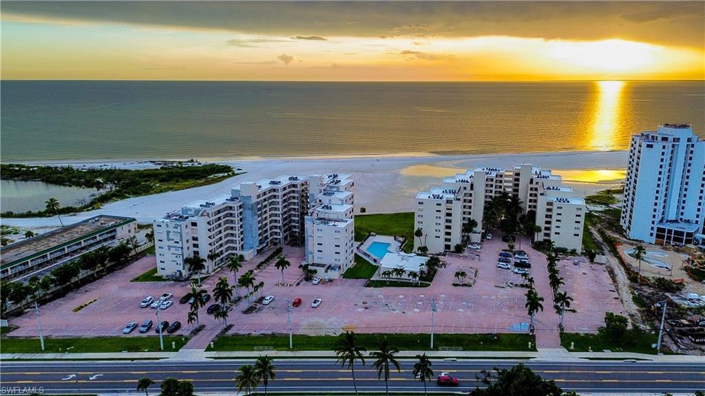 Image 1: Aerial view at dusk of a view of apartment building / complex and view of water and beach