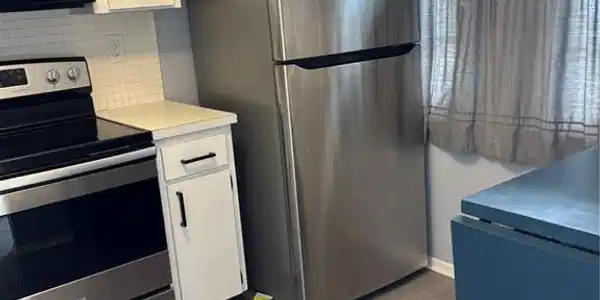 Image 3: Kitchen featuring range, stainless steel fridge, white cabinets, light countertops, and wood finished floors