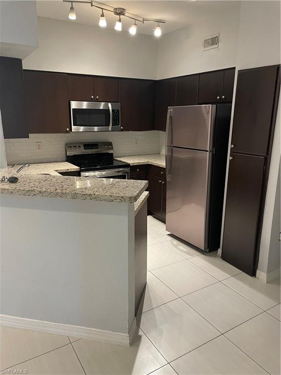 Image 1: Kitchen featuring dark wood-finish cabinetry, light-colored granite countertops, and a white subway tile backsplash