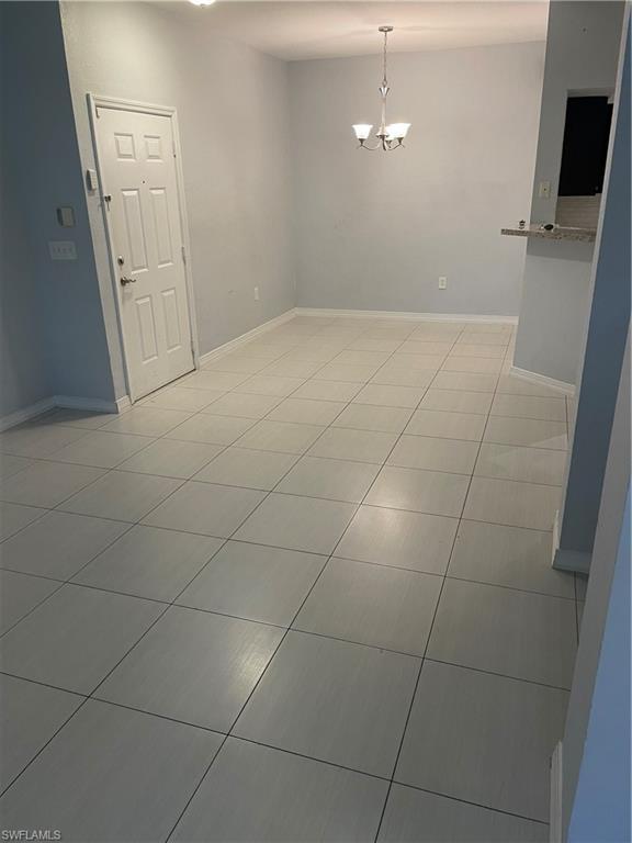 Image 2: Expansive interior room featuring light-toned tile flooring, neutral wall tones, and a decorative ceiling light fixture
