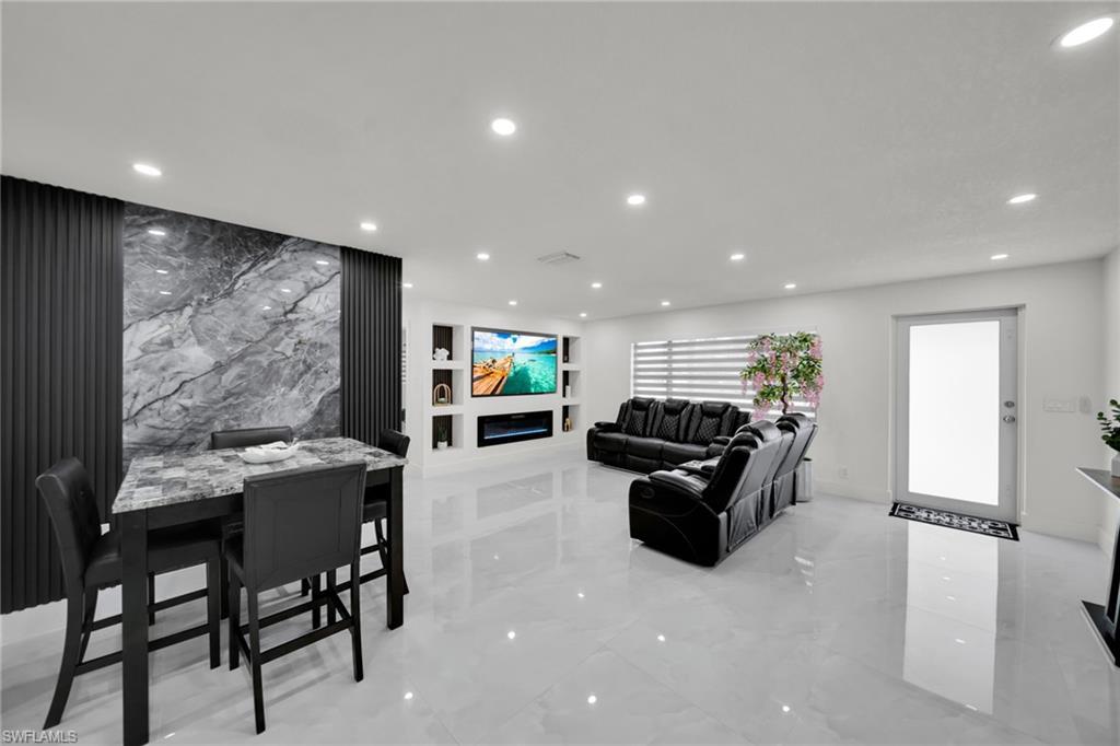 Image 4: Open-concept living area featuring high-gloss tile flooring, recessed lighting, and a contemporary accent wall with vertical paneling and a central stone-finish section