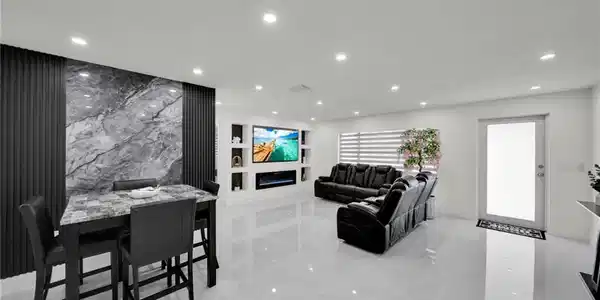 Image 4: Open-concept living area featuring high-gloss tile flooring, recessed lighting, and a contemporary accent wall with vertical paneling and a central stone-finish section