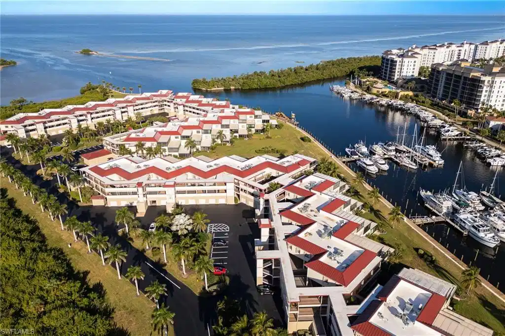 Image 1: Coastal community featuring waterfront properties, a private marina with multiple boat slips, extensive landscaping with palm trees, and direct access to open water