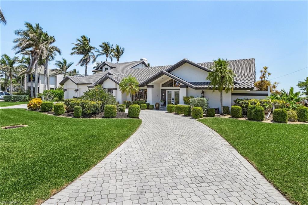 Image 2: View of front of house with a tile roof, a front lawn, stucco siding, decorative driveway, and french doors