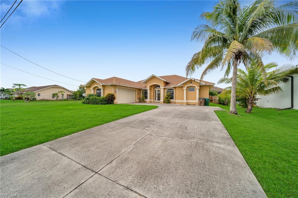 Image 2: View of front of house with driveway, a front lawn, stucco siding, and an attached garage
