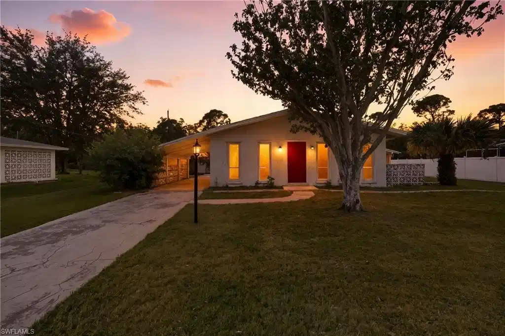Image 1: Mid-century home with concrete driveway, stucco siding, and a carport