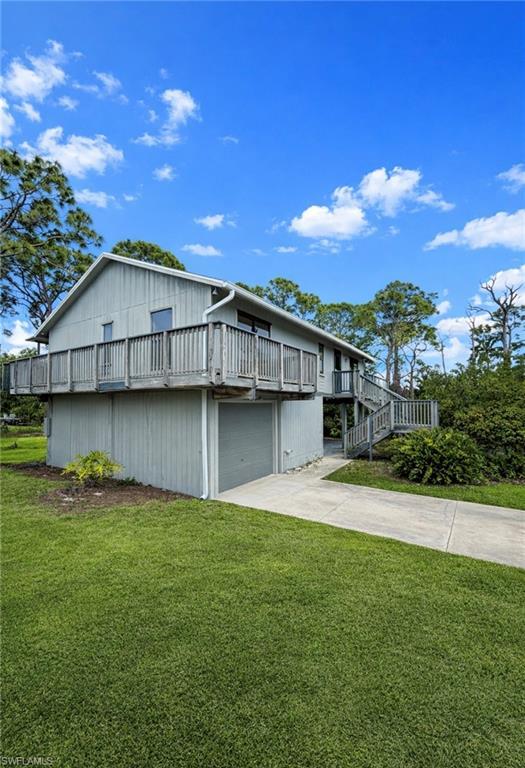 Image 2: Back of house featuring a lawn, concrete driveway, an attached garage, and a balcony