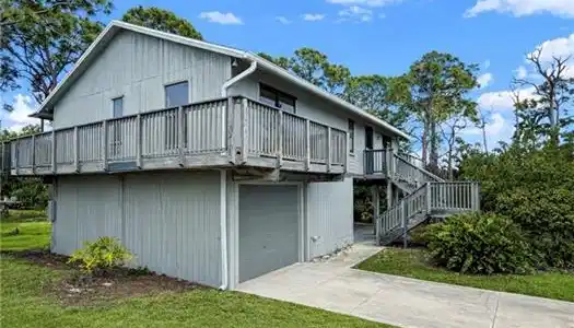 Image 2: Back of house featuring a lawn, concrete driveway, an attached garage, and a balcony
