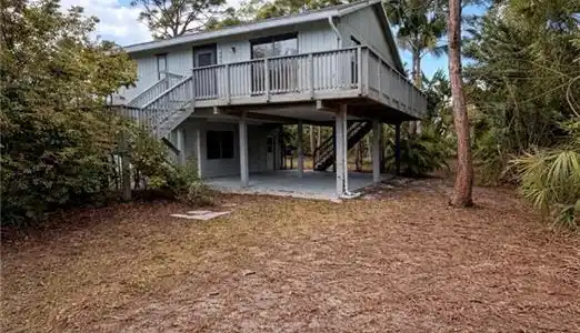 Image 3: Rear view of property featuring a wooden deck, a patio, and a carport